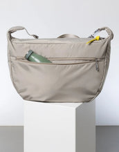 Laden Sie das Bild in den Galerie-Viewer, Padded Hip Bag Oversized von Vivi Mari in Stone, große wasserabweisende Umhängetasche mit zwei Außentaschen, verstellbarem Schultergurt und silbernen Metallakzenten, aus recyceltem Polyester.