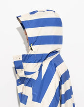 Laden Sie das Bild in den Galerie-Viewer, Raincoat Bold Stripes Blue/Sand von VIVI MARI – wasserdichtes Cape aus recyceltem Polyester in Oversize-Passform mit Kapuze, Klettverschluss-Manschetten und seitlichen Taschen, nachhaltig und funktional für Stadt, Fahrrad und Alltag