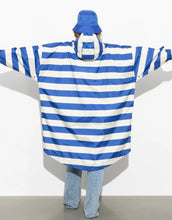 Laden Sie das Bild in den Galerie-Viewer, Raincoat Bold Stripes Blue/Sand von VIVI MARI – wasserdichtes Cape aus recyceltem Polyester in Oversize-Passform mit Kapuze, Klettverschluss-Manschetten und seitlichen Taschen, nachhaltig und funktional für Stadt, Fahrrad und Alltag