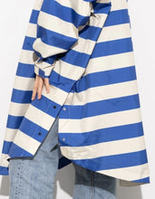 Laden Sie das Bild in den Galerie-Viewer, Raincoat Bold Stripes Blue/Sand von VIVI MARI – wasserdichtes Cape aus recyceltem Polyester in Oversize-Passform mit Kapuze, Klettverschluss-Manschetten und seitlichen Taschen, nachhaltig und funktional für Stadt, Fahrrad und Alltag