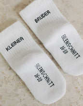Laden Sie das Bild in den Galerie-Viewer, Babysocken Kleiner Bruder von Eulenschnitt, 80% Baumwolle, 18% Polyamid, 2% Elastan, mit Schriftzug „Kleiner Bruder“ auf dem Bündchen.