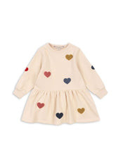 Laden Sie das Bild in den Galerie-Viewer, Beige Lou Sweat Dress von Konges Sløjd mit bunten Herz-Patches, ausgestelltem Rock und Rundhalsausschnitt.