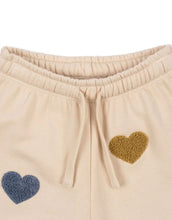 Laden Sie das Bild in den Galerie-Viewer, Beige-rosefarbene Lou Sweatpants von Konges Sløjd mit bunten Herzen und elastischem Bund.
