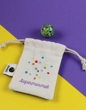 Laden Sie das Bild in den Galerie-Viewer, Ava & Yves Supermurmel Grün – Muranoglas-Murmel (25 mm) mit bunten Konfetti-Steinchen im bestickten Stoffbeutel.