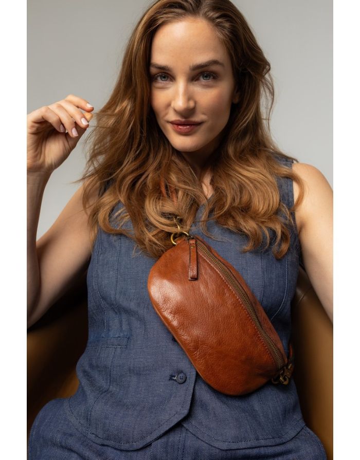 Braune Gisela Bumbag von RE:DESIGNED aus hochwertigem Rindsleder in der Farbe Walnut mit verstellbarem Schultergurt und zeitlosem Design mit Model