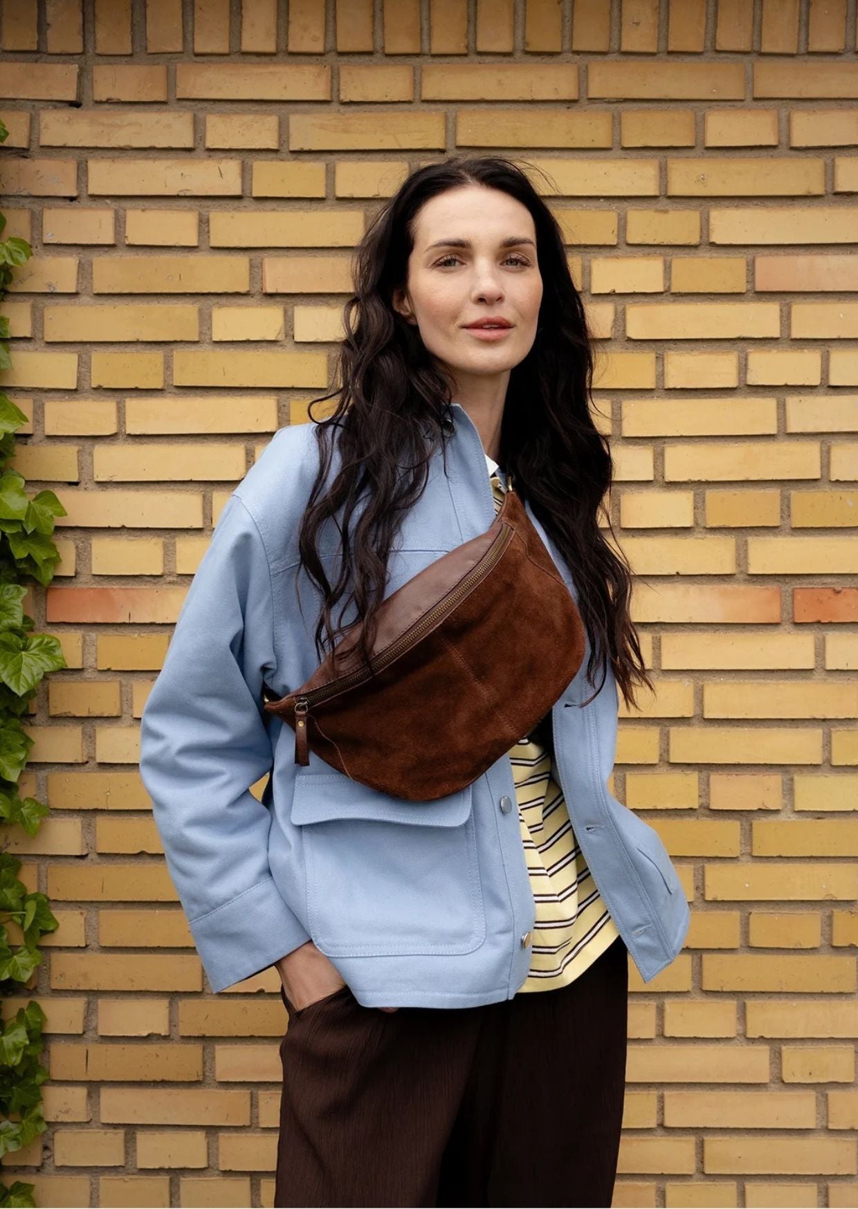 Bauchtasche Selma von Re:Designed in Woodsmoke aus weichem Veloursleder mit verstellbarem Crossbody-Gurt und Reißverschluss.