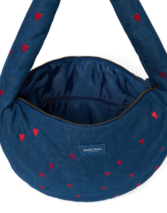 Studio Noos Cross Body Umhängetasche aus dunkelblauem gepolstertem Denim mit gestickten roten Herzen und Platz für einen 13-Zoll-Laptop geöffnet.