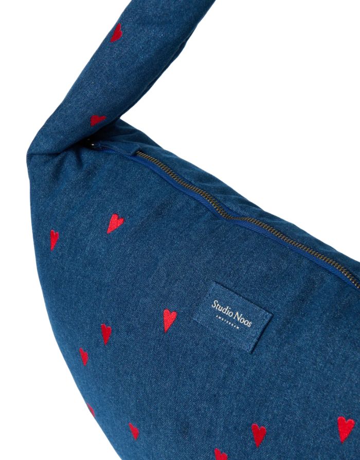Studio Noos Cross Body Umhängetasche aus dunkelblauem gepolstertem Denim mit gestickten roten Herzen und Platz für einen 13-Zoll-Laptop nah.