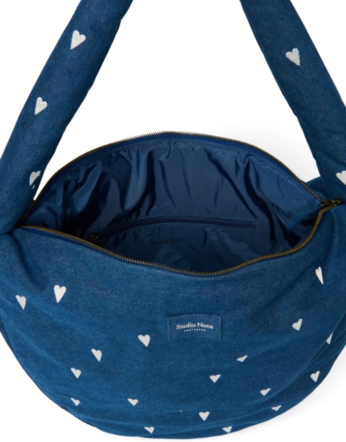 Studio Noos Cross Body Umhängetasche aus dunkelblauem gepolstertem Denim mit gestickten weißen Herzen und Platz für einen 13-Zoll-Laptop, geöffnet.