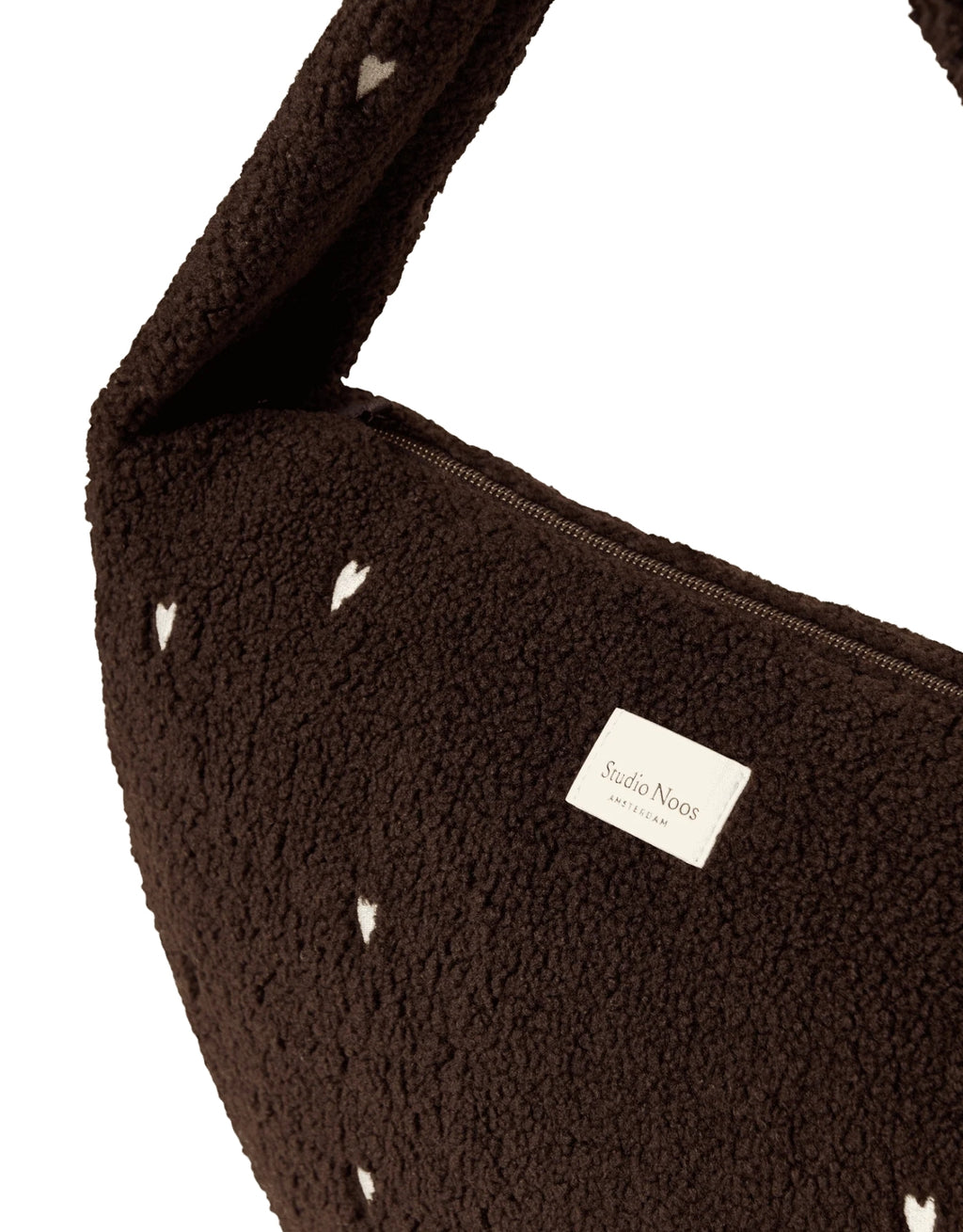 Schokoladenbraune Cross Body Umhängetasche Chocolate Teddy Hearts von Studio Noos aus weichem Teddy-Material und aufgestickten weißen Herzen mit Seitentaschen und Platz für einen 13-Zoll-Laptop.