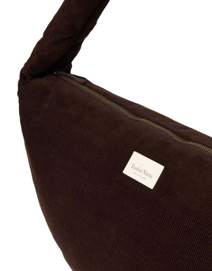 Studio Noos Crossbody Umhängetasche Rib Puffy in Dark Brown aus gepolstertem Rib-Stoff mit Seitentaschen und Platz für einen 13-Zoll-Laptop, Nahaufnahme.