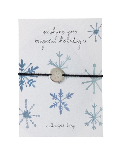 Schmuck-Postkarte Crystals von A Beautiful Story mit Schneekristallen, „wishing you magical holidays“-Schriftzug und Armband mit Sternanhänger.