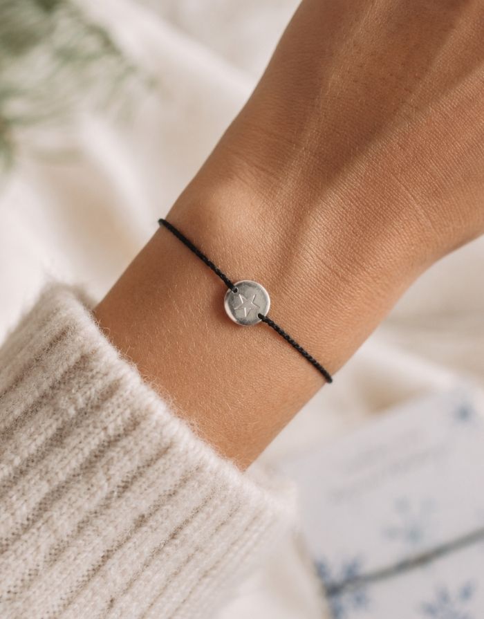 Schmuck-Postkarte Crystals von A Beautiful Story mit Schneekristallen, „wishing you magical holidays“-Schriftzug und Armband mit Sternanhänger, getragen.