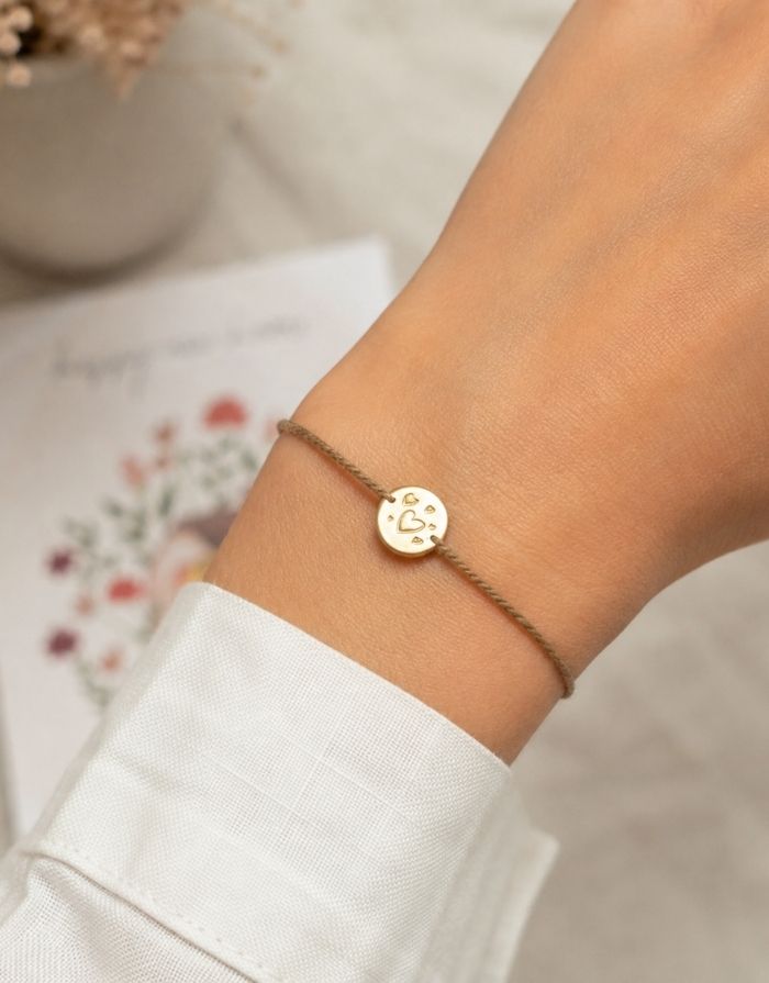 Schmuck-Postkarte New Home von A Beautiful Story mit „happy new home“-Hausmotiv und Armband mit vergoldetem Herzanhänger, getragen.