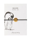 Schmuck-Postkarte Pinguin von A Beautiful Story mit „welcome little one“-Motiv und schwarzem Armband mit goldfarbenem Sternanhänger.