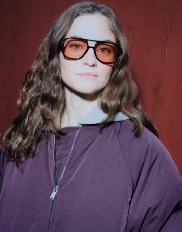 CHPO Cocas Sonnenbrille mit glänzend schwarzem Gestell, hellorange getönten Gläsern, UV400-Schutz und Gestell aus 100 % recyceltem Kunststoff am Model.