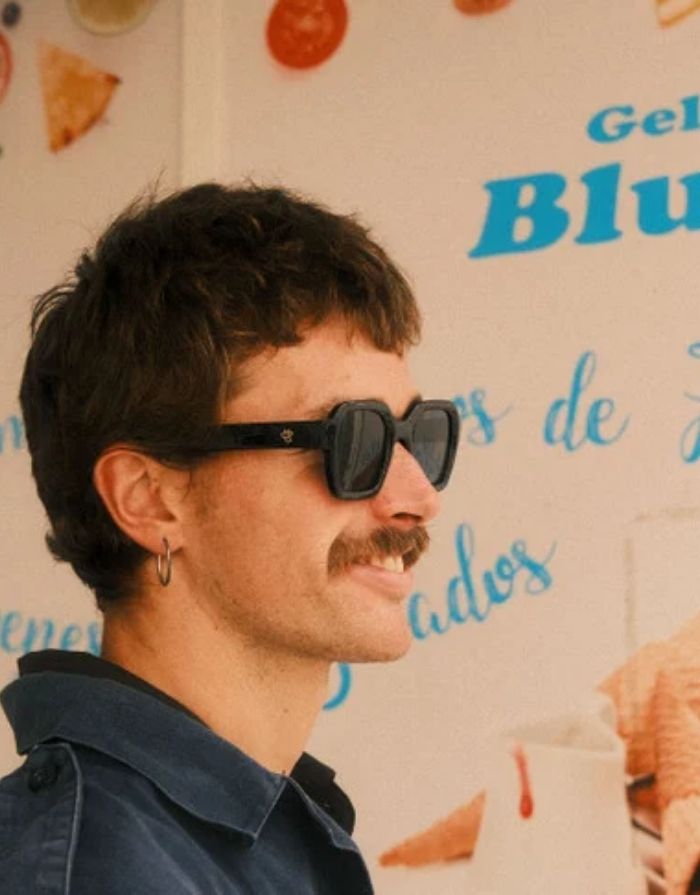 CHPO AK Sonnenbrille mit glänzend schwarzer Fassung, schwarzen Gläsern und UV400-Schutz aus recyceltem Kunststoff getragen.