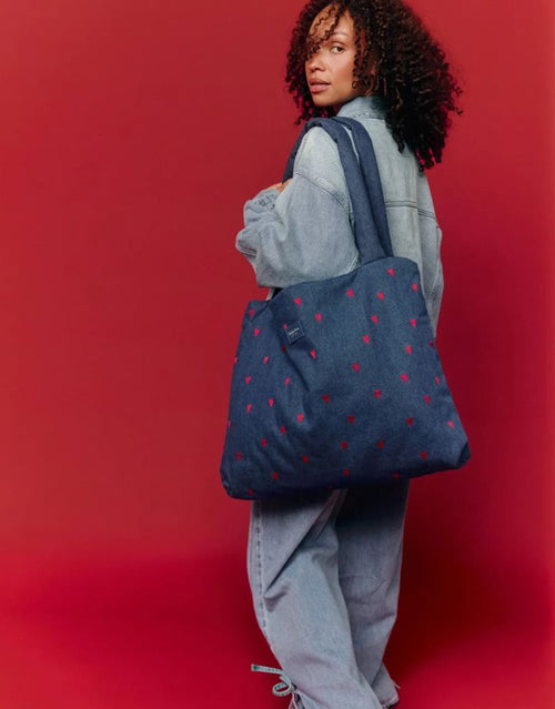 Studio Noos Mom Bag aus dunkelblauem gepolstertem Denim mit roten Herzen, langen Tragegriffen und geräumigem offenem Hauptfach, getragen.