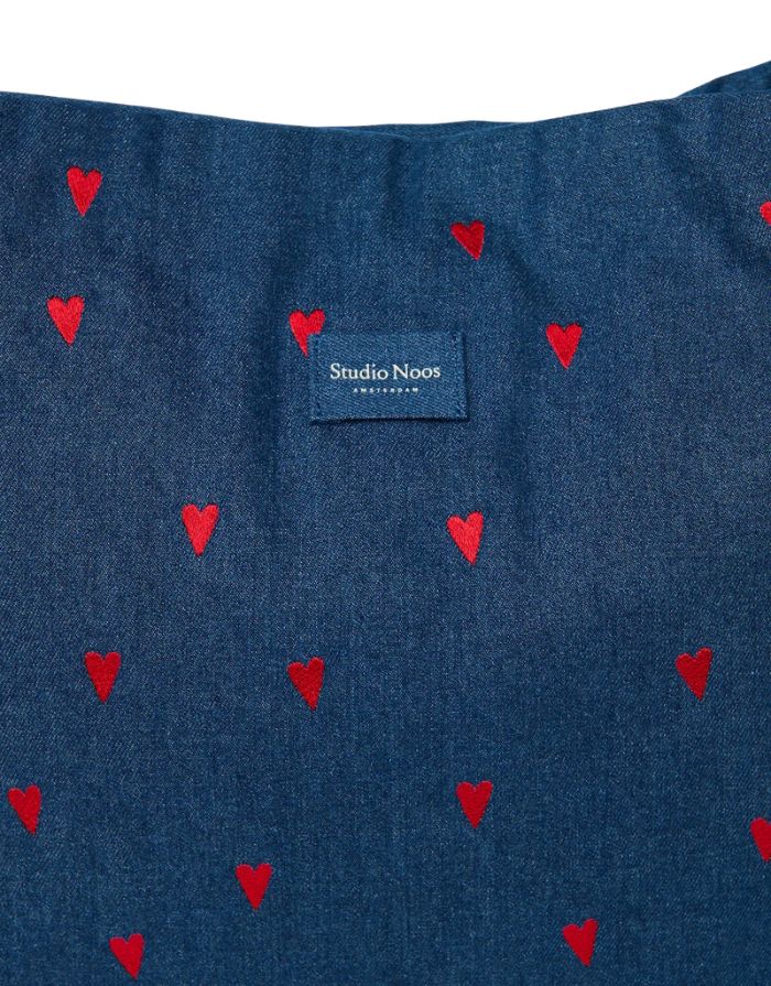 Studio Noos Mom Bag aus dunkelblauem gepolstertem Denim mit roten Herzen, langen Tragegriffen und geräumigem offenem Hauptfach, Nahaufnahme.
