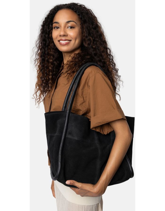 Schwarze Meno Schultertasche von RE:DESIGNED aus weichem Veloursleder mit großzügigem Hauptfach und Lederhenkel Seitlich am Model