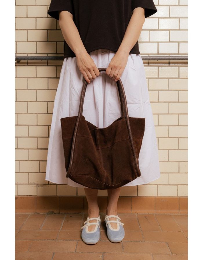  Braune Meno Schultertasche von RE:DESIGNED aus weichem Veloursleder in der Farbe Woodsmoke mit großzügigem Hauptfach und Lederhenkel vor dem Model