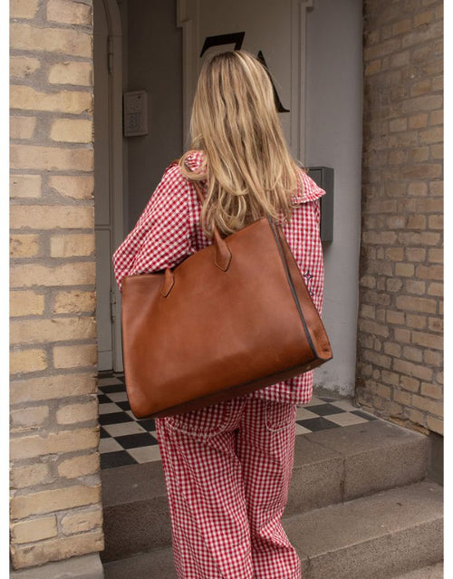  Braune Ora Big Ledertasche von Re:Designed mit großem Hauptfach, praktischen Innenfächern und handgefertigtem Design getragen