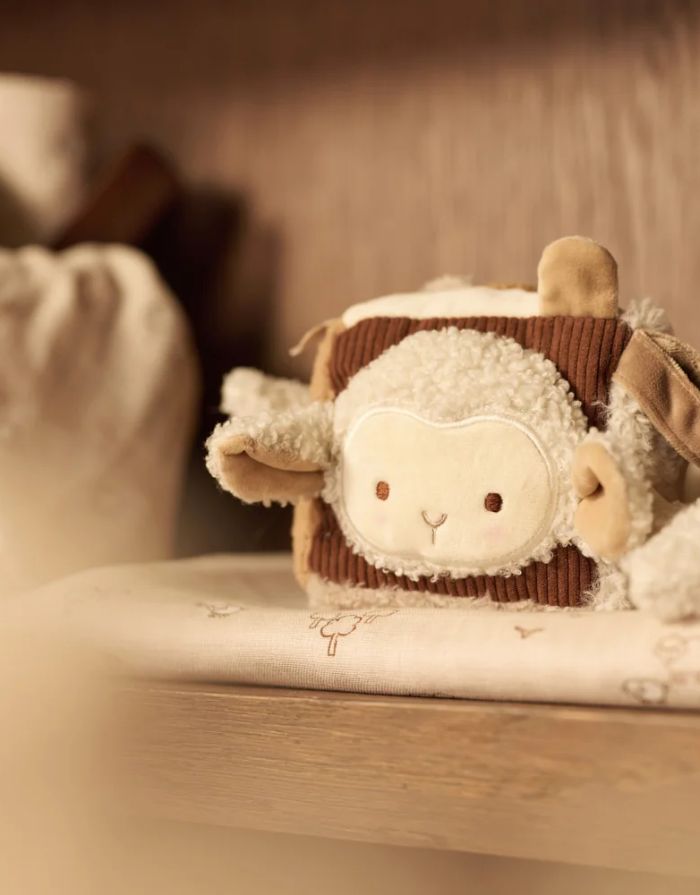 ein Aktivitäten-Würfel Woolly mit Schäfchen, Spiegel, Knisterelementen, Glöckchen und Befestigungsring für Babys.