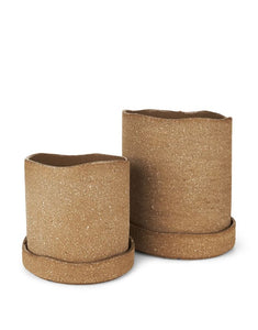 Brauner Übertopf Uneru von Ferm Living mit rauer Oberfläche, unregelmäßigen Kanten und passender Untertasse aus recyceltem Steingut, innen glasiert.