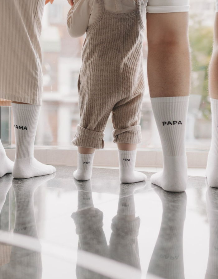 Weiße Babysocken Mini von Eulenschnitt mit schwarzem Schriftzug für Babys im Alter von 3 Monaten