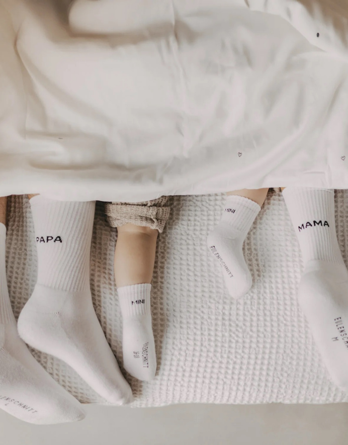 Weiße Babysocken Mini von Eulenschnitt mit schwarzem Schriftzug für Babys im Alter von 3 Monaten
