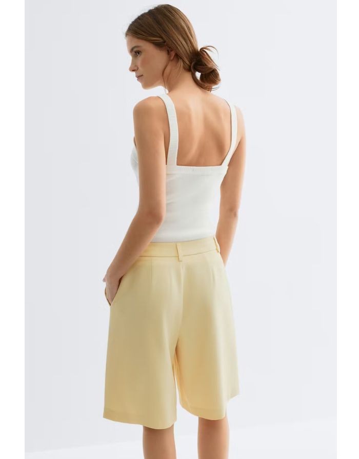 Gina Tricot Bermuda Shorts Butter Yellow mit geradem Bein und Bügelfalten in knielanger Passform an Model von hinten