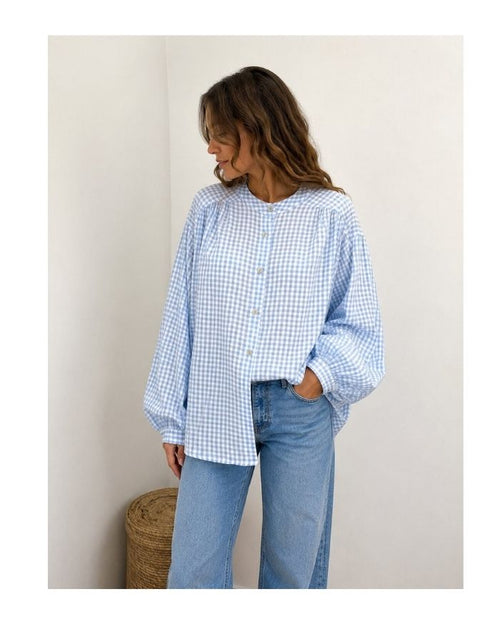 Bluse Karo Light Blue von MAËLYS PARIS mit Vichy-Karomuster, Rundhalsausschnitt und langen Ärmeln mit geknöpften Manschetten.