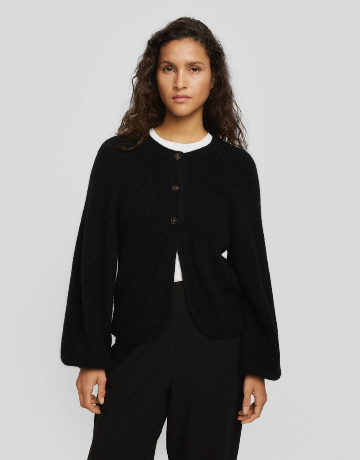 Schwarzer Cilia Hope Cardigan von MSCH Copenhagen aus weichem Woll-Alpaka-Mix mit Rundhalsausschnitt, drei Knöpfen und abgerundeter Vorderseite am Model von vorne