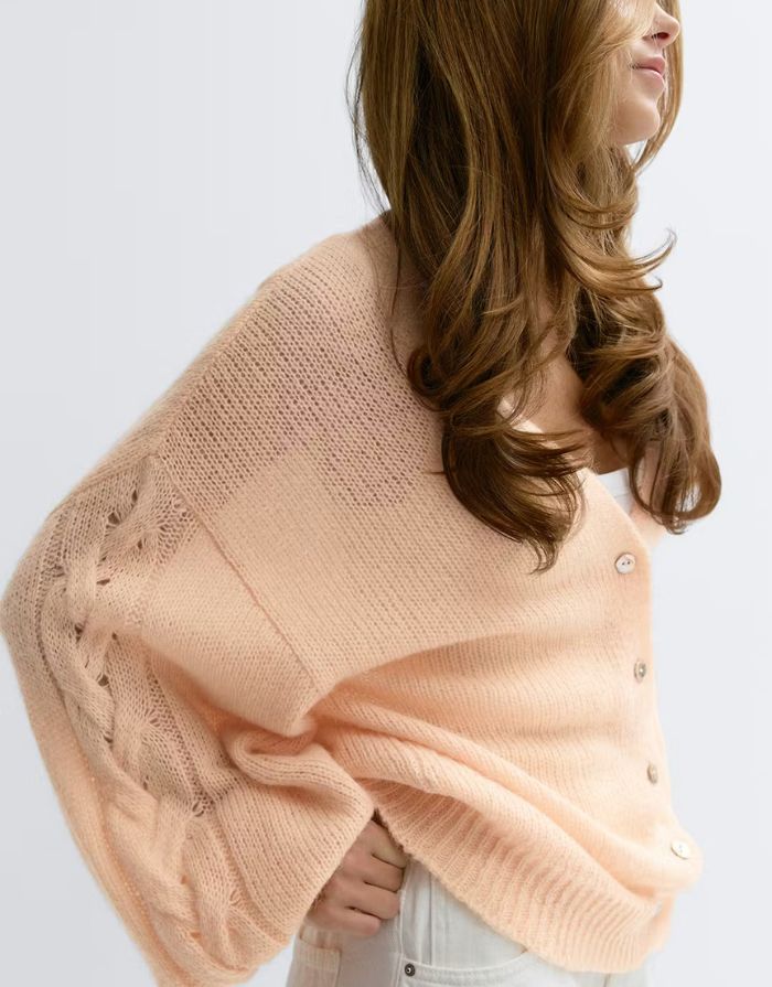 Gina Tricot Oversize Strickjacke Bellini in Pfirsich mit V-Ausschnitt und Knopfleiste an Model von der Seite