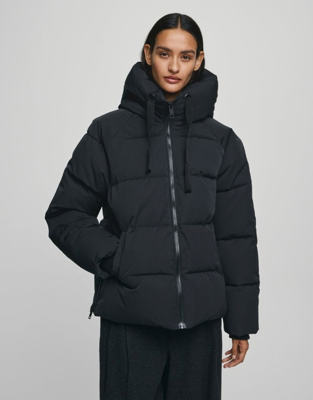 Schwarze kurze Winterjacke Pavinaria Short von MSCH Copenhagen mit Kapuze, hohem Kragen, leichter Wattierung und seitlichen Reißverschlüssen.