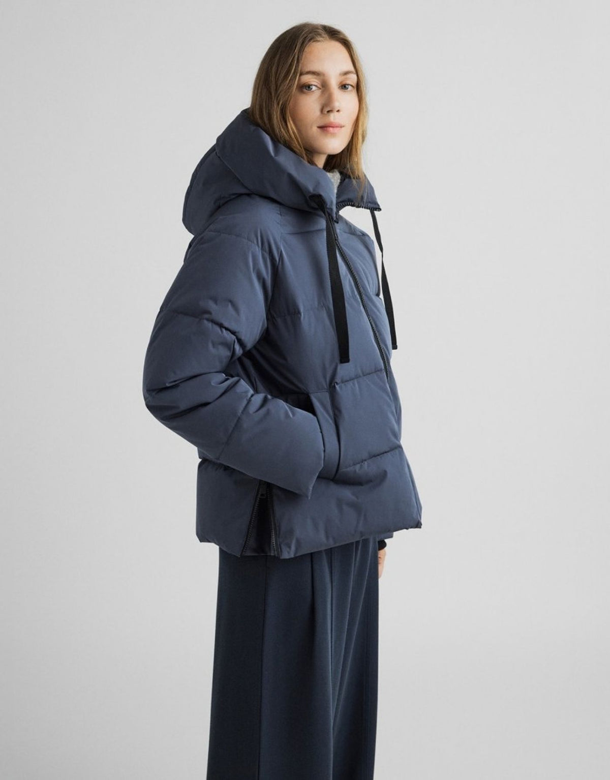 Dunkelblaue kurze Winterjacke Pavinaria Short von MSCH Copenhagen in India Ink mit Kapuze, hohem Kragen, leichter Wattierung und seitlichen Reißverschlüssen getragen