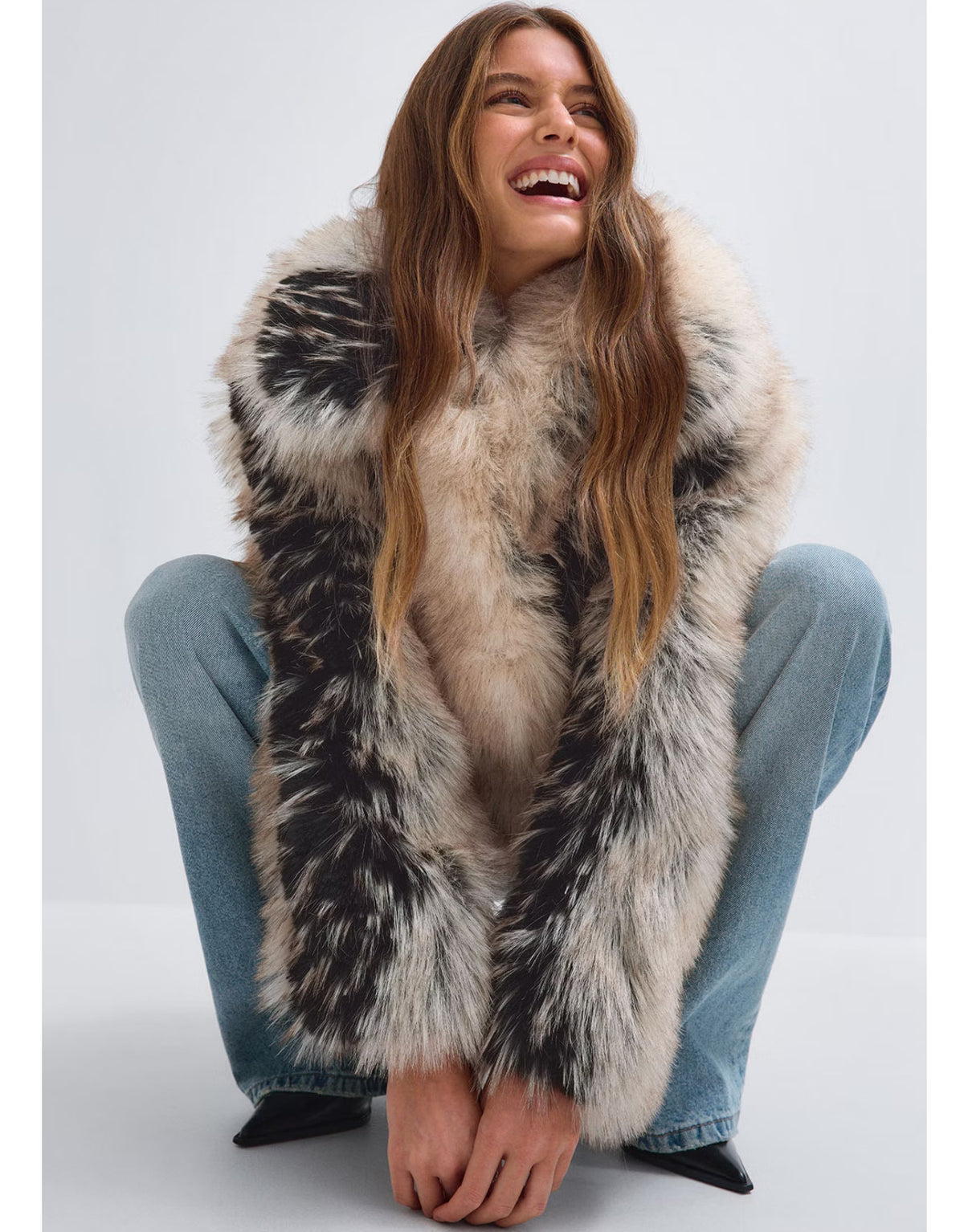 Cremeweiß-schwarze Faux Fur Short Jacke von Gina Tricot mit flauschigem Kunstfell, breitem Kragen, Knopfverschluss und kurzer Oversize-Silhouette am Model im Sitzen