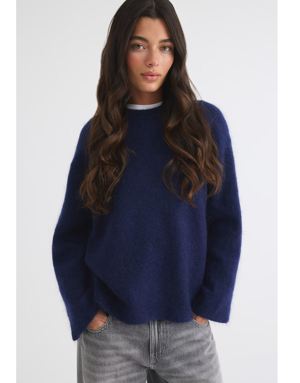 Dunkelblauer Mohair Pullover von Gina Tricot mit feiner, flauschiger Strickstruktur, lockerer Passform, langen Ärmeln und klassischem Rundhalsausschnitt am Model von vorne