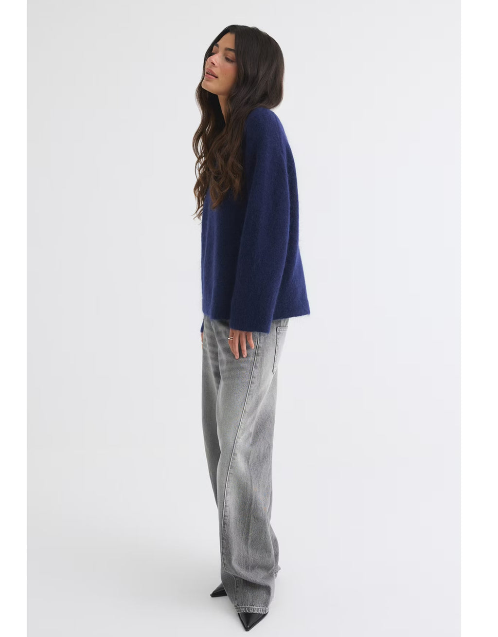 Dunkelblauer Mohair Pullover von Gina Tricot mit feiner, flauschiger Strickstruktur, lockerer Passform, langen Ärmeln und klassischem Rundhalsausschnitt am Model von der Seite