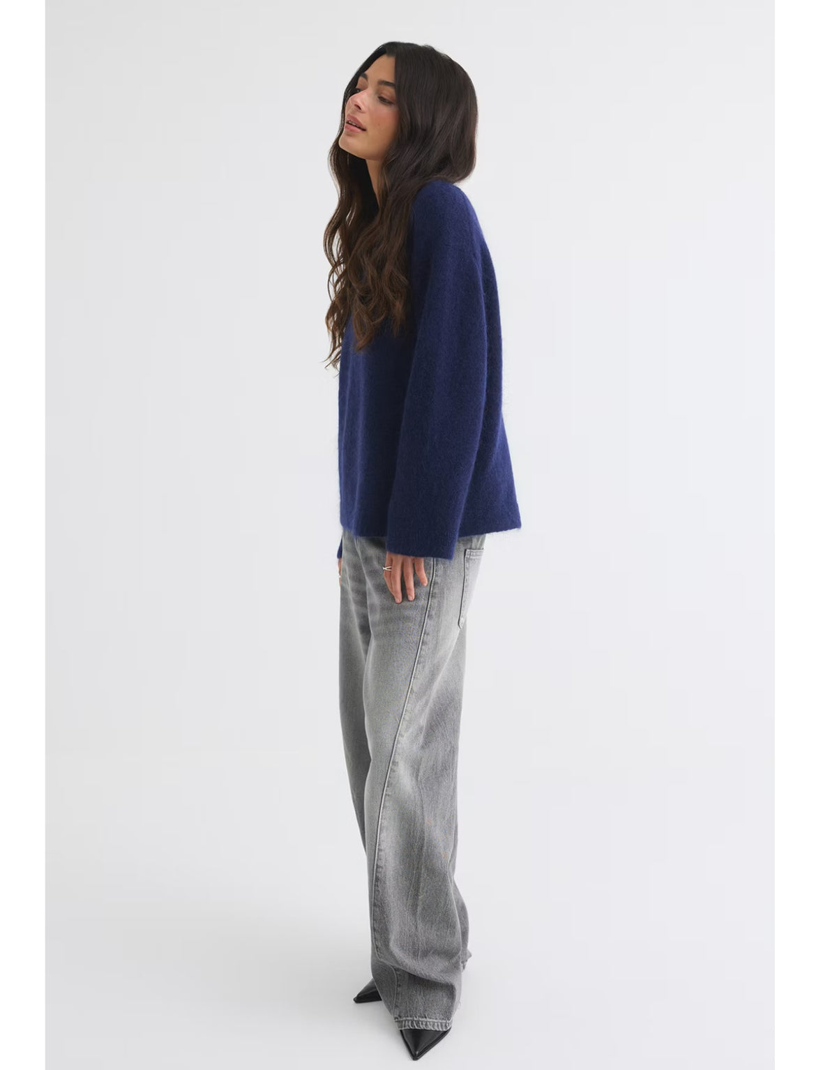 Dunkelblauer Mohair Pullover von Gina Tricot mit feiner, flauschiger Strickstruktur, lockerer Passform, langen Ärmeln und klassischem Rundhalsausschnitt am Model von der Seite