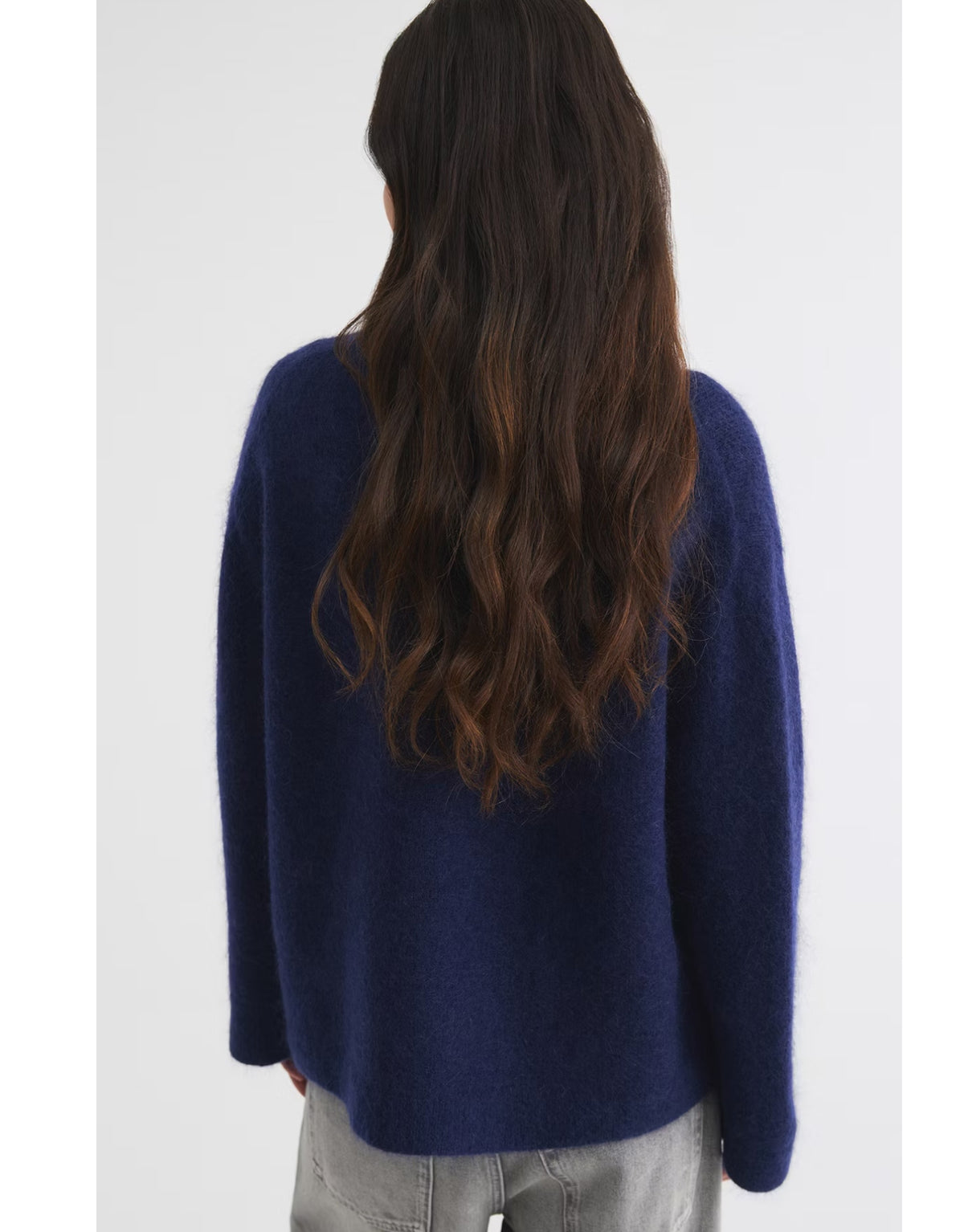 Dunkelblauer Mohair Pullover von Gina Tricot mit feiner, flauschiger Strickstruktur, lockerer Passform, langen Ärmeln und klassischem Rundhalsausschnitt am Model von hinten 