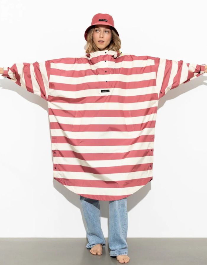 Raincoat Bold Stripes Blush/Sand von VIVI MARI: Langer, wasserdichter Regenmantel im Streifen-Design, oversized geschnitten mit Kapuze, Knopfleiste, Klettverschluss-Manschetten und praktischen Taschen – nachhaltig aus recyceltem Polyester gefertigt.