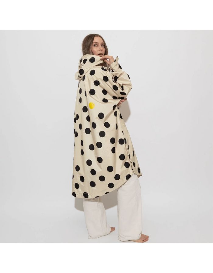 Raincoat Bold Stripes Dots Black/Sand von VIVI MARI: Langer, wasserdichter Regenmantel im Streifen-Design, oversized geschnitten mit Kapuze, Knopfleiste, Klettverschluss-Manschetten und praktischen Taschen – nachhaltig aus recyceltem Polyester gefertigt.