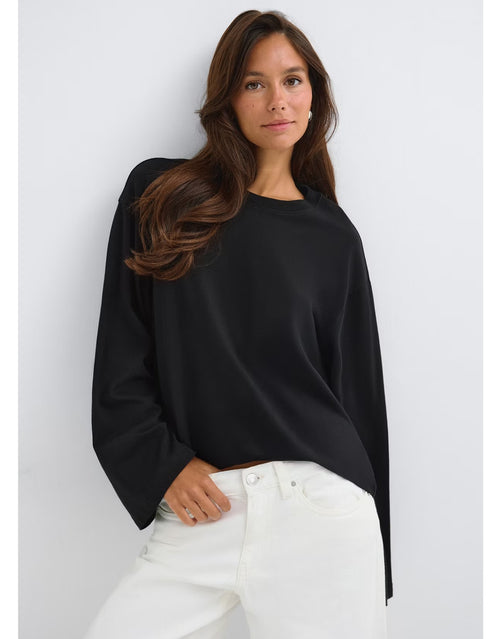 Schwarzes Loose Fit Long Sleeve Shirt von Gina Tricot mit lässiger Oversize-Passform, langen Ärmeln und klassischem Rundhalsausschnitt am Model