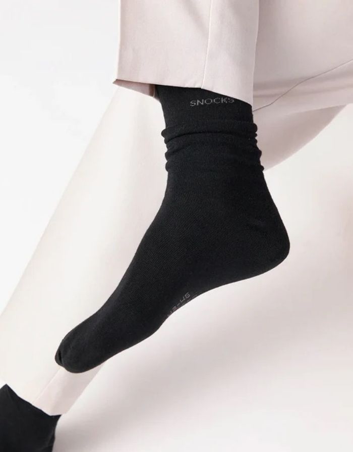 Schwarze Business-Socken von Snocks aus Bio-Baumwolle mit komfortabler Passform und knielanger Form für den Büroalltag am Model ohne Schuh