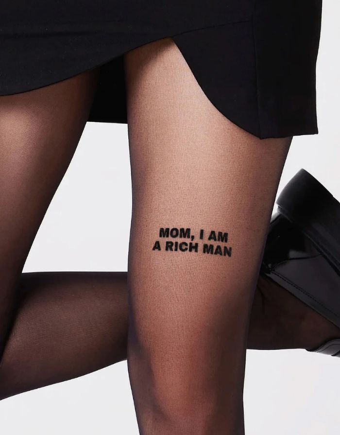 Schwarze semi-transparente Statement-Strumpfhose Mom, I Am A Rich Man von saint sass mit 40 DEN und Schriftzug am vorderen Oberschenkel.