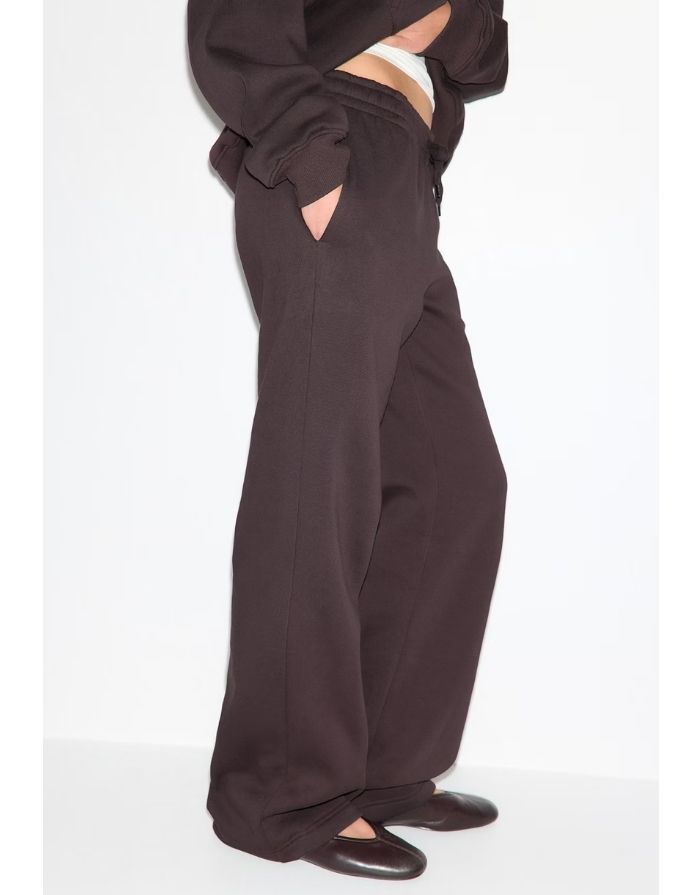 Gina Tricot Iconic Sweat Pants in Chocolate Plum aus Baumwollmischung mit weitem geradem Bein, elastischem Bund, Bindeband und Seitentaschen am Model von der Seite