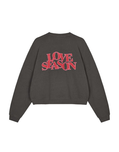  Light Love Season Sweater von OH APRIL in Graphite mit großem Love-Season-Print auf dem Rücken und kleinem Logo auf der Brust, entspannte Passform, leicht verkürzt, aus weichem Baumwollmix mit klassischem Rundhalsausschnitt.