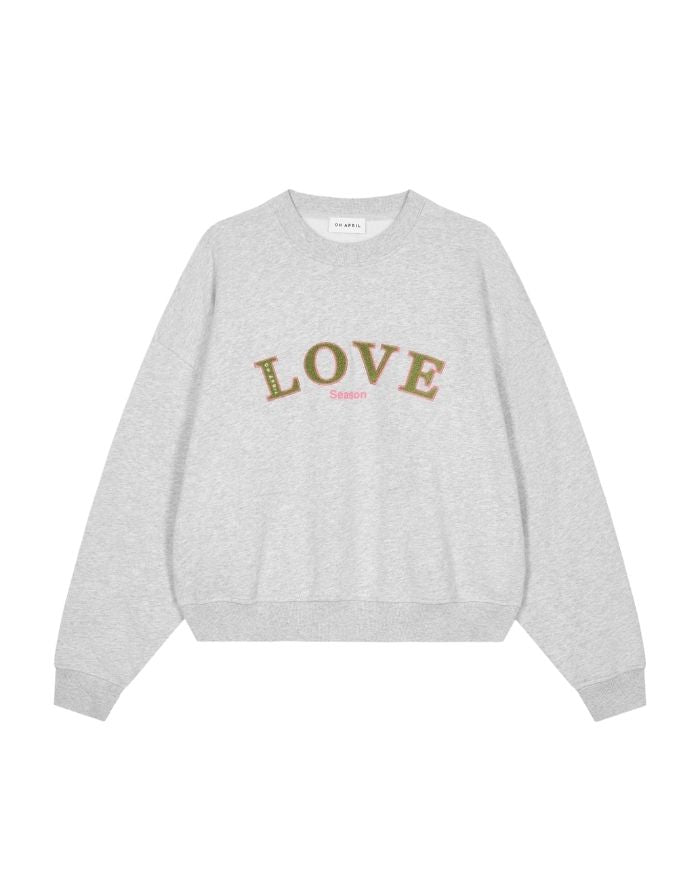 Regular Love Sweater von OH APRIL in Grey Melange mit dezentem Love-Season-Print auf der Brust, entspannter Schnitt, leicht verkürzt, aus weichem Baumwollmix mit klassischem Rundhalsausschnitt.
