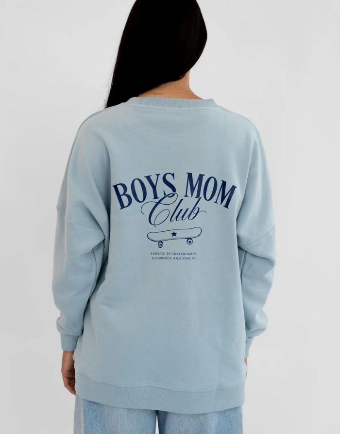  Liliput Boys Mom Club Oversize Sweatshirt für Damen mit dezentem Brustprint und großem Skateboard-Schriftzug auf dem Rücken, getragen.